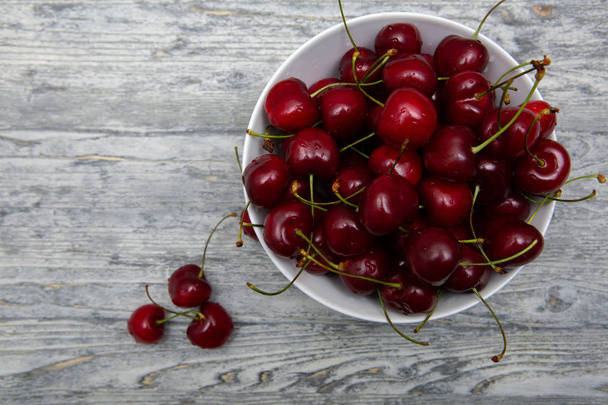 cherries in white bowl on wooden background - Φωτογραφία, εικόνα