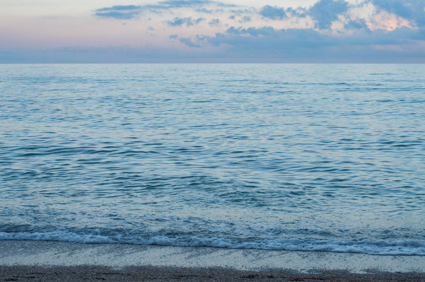 Acqua di mare ondulata in blu sera crepuscolo viola con pittoresco paesaggio nuvoloso. Mare di costa del Mar Nero. Ondeggiando maree del mare vengono a sabbia bagnata spiaggia. Paesaggio di viaggio. Tranquillo paesaggio marino. Vacanze estive relax
  - Foto, immagini