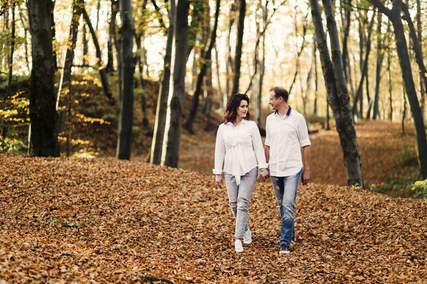 Romantic young couple walking in autumn park. Family together in the park. Pregnant couple. - 写真・画像
