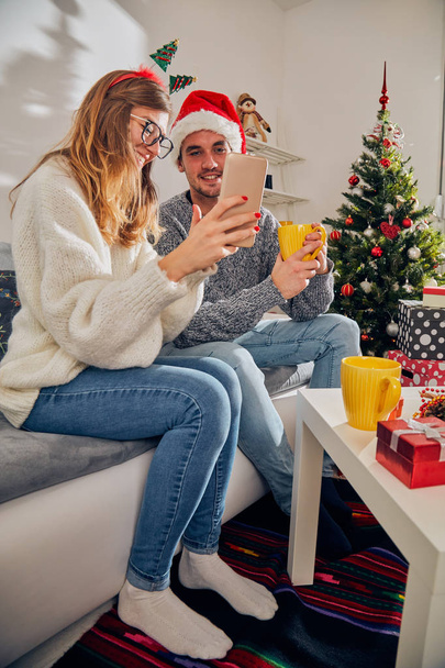 Happy couple enjoying New Year 's / Christmas eve with cell phone
  - Фото, изображение