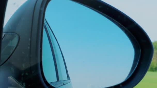 Blue sky and trees reflection in right side rear view mirror during automobile driving on highway. Vacation, weekend concept. Sitter, passenger perspective inside of car. Transportation, transport. Traveling, driver view to black rear view mirror - Footage, Video
