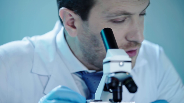 przystojny naukowiec rozmawia podczas patrzenia w Mikroskop w laboratorium - Materiał filmowy, wideo