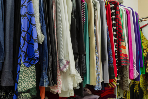 Beautiful colorful clothes in a store on hangers. - Photo, Image