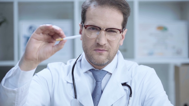 vakava lääkäri lasit esittelee savukkeen katsellessaan kameraa ja osoittaa paheksuva merkki
 - Materiaali, video