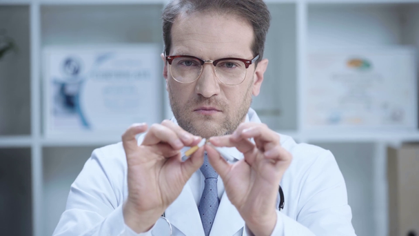 serious doctor in glasses braking cigarette and looking at camera - Footage, Video