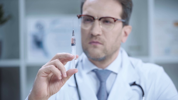 vakava lääkäri valkoisessa takissa ja lasit sumutusnestettä ruiskusta
  - Materiaali, video