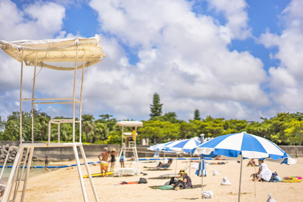 Пляжные пумбреллы и спасательные кресла на песчаном пляже Наминоуэ в городе Окинава префектуры Окинава, Япония
. - Фото, изображение