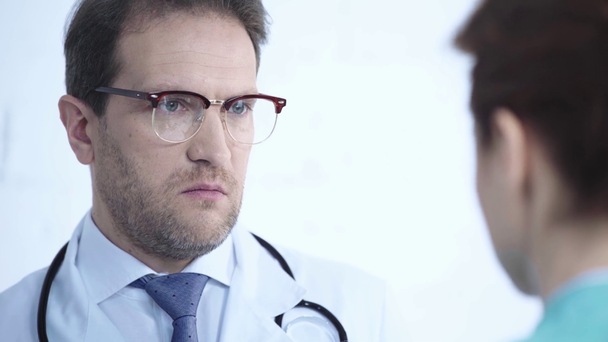 селективное внимание привлекательного врача в очках, разговаривающего с медсестрой в больнице
 - Кадры, видео