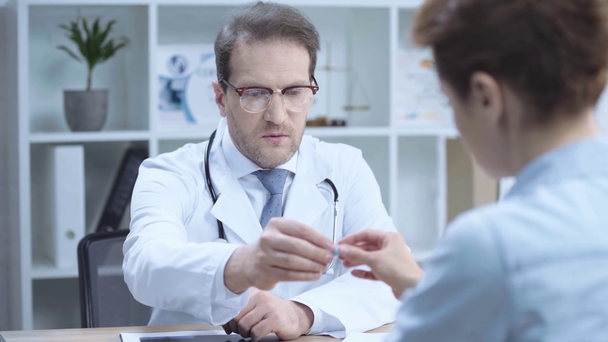 komea lääkäri puhuu sairaanhoitajalle ja antaa hänelle pilleri istuessaan työpaikalla sairaalassa
 - Materiaali, video