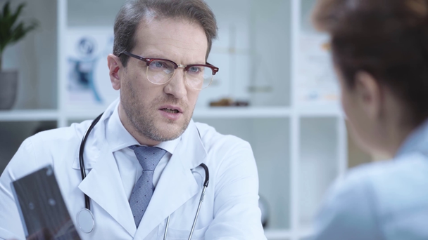 selectieve focus van knappe dokter kijkend naar x-ray diagnose en praten met collega - Video