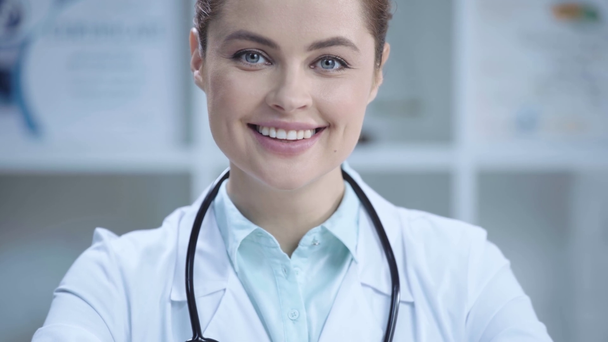 mooie jonge dokter glimlachend en kijkend naar camera in het ziekenhuis - Video