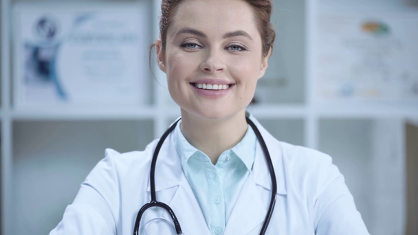 vrolijke jonge dokter in witte vacht glimlachend en kijkend naar de camera  - Video