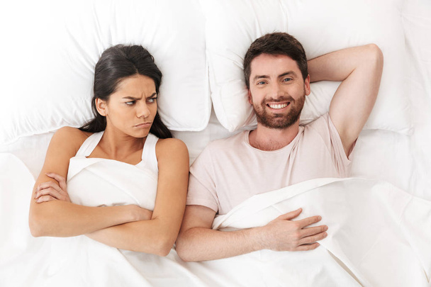 Displeased quarrel young loving couple lies in bed under blanket. - Photo, image