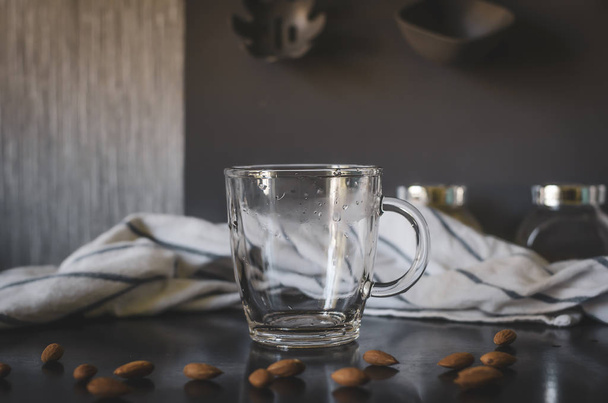 Glass empty mug. Around almonds, staged photo. - Foto, Bild