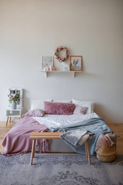 Real photo of the bright cozy bedroom interior with panoramic window. King size bed on the wooden floor, gray carpet, white wall with eco-themed posters . Wicker chair in front of the window. - Φωτογραφία, εικόνα