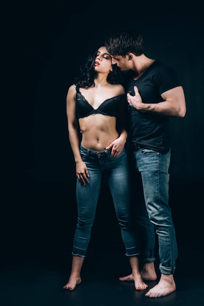 barefoot couple in denim passionately undressing isolated on black  - Fotoğraf, Görsel