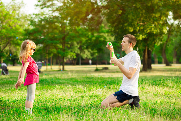 Father and daughter playing in the park at the day time. Concept of friendly family. - 写真・画像
