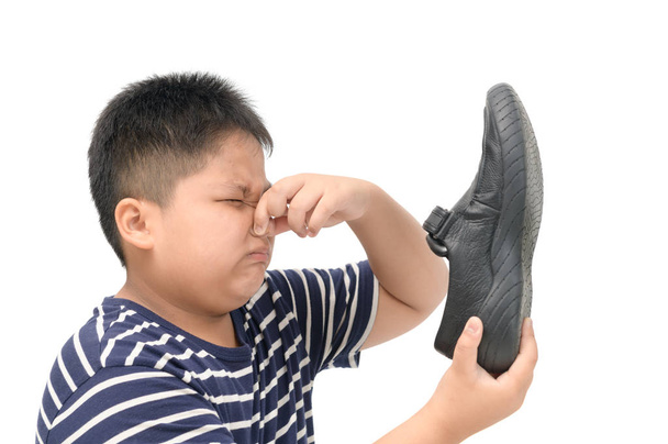 Disgusted boy holding a pair of smelly leather shoes  - Photo, Image