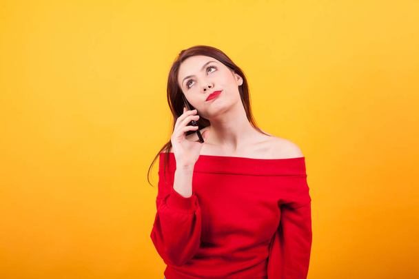 Yelloq arka plan üzerinden telefonda konuşurken sıkılmış güzel genç kadın Portresi - Fotoğraf, Görsel