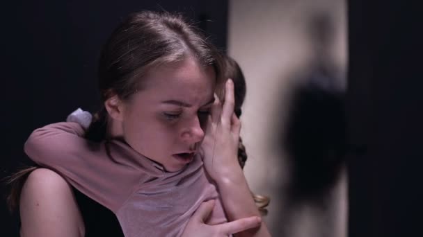 Mujer asustada abrazando a su hija, asustada por un hombre cruel con cinturón entrando en la habitación
 - Metraje, vídeo