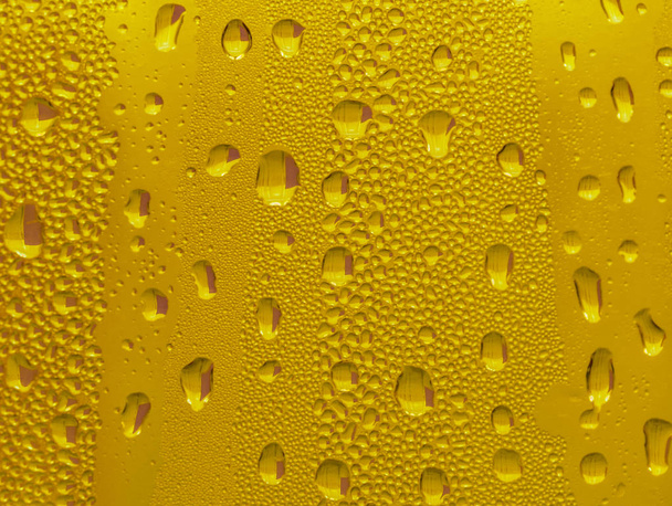 Gouttes d'eau sur le verre, bière de fond jaune, fond brumeux
. - Photo, image