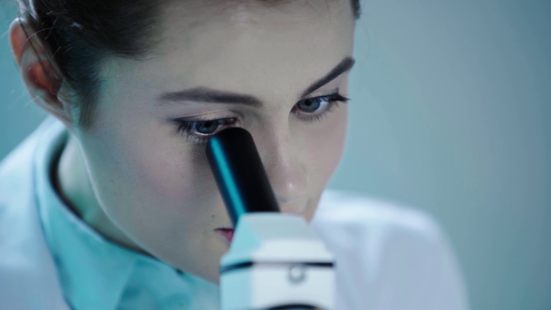 ελκυστική, προσεκτική επιστήμονας κάνοντας έρευνα με μικροσκόπιο και μιλώντας σε εργαστηριακές - Πλάνα, βίντεο