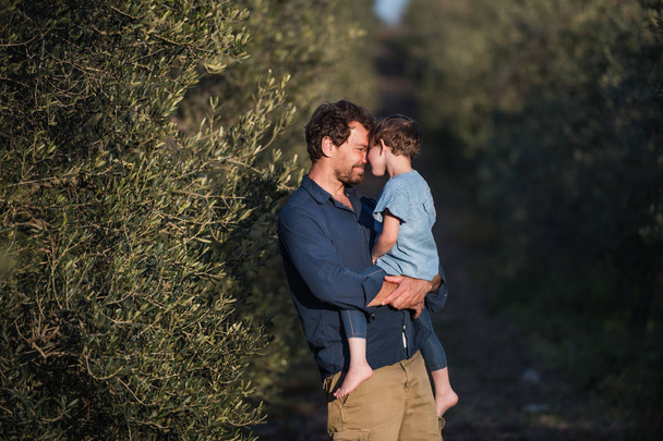Father with small daughter standing outdoors by olive tree. - Fotografie, Obrázek