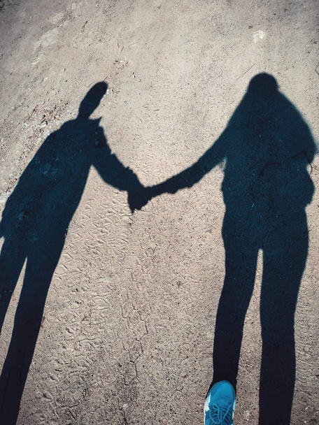 La silhouette d'un couple aime couler main dans la main l'amour sur une longue ombre dans la rue.Les ombres des piétons ambulants projetées sur le trottoir. Photo artistique en noir et blanc, B & W le jour ensoleillé
 - Photo, image