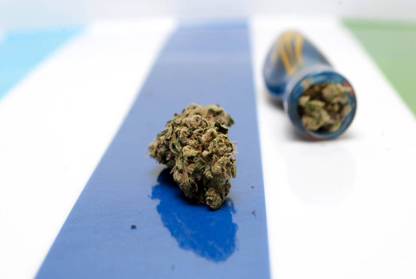 Dried marijuana and blue smoking pipe on colorful striped background. Drug addiction concept. Medical marijuana concept  - Photo, image