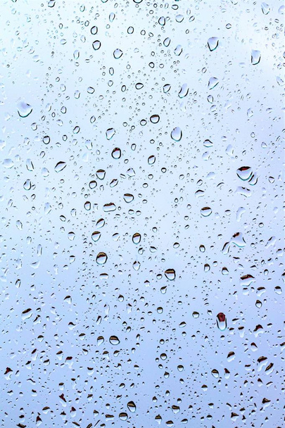Gotas de chuva no vidro, fundo azul escuro do céu fora da janela
. - Foto, Imagem