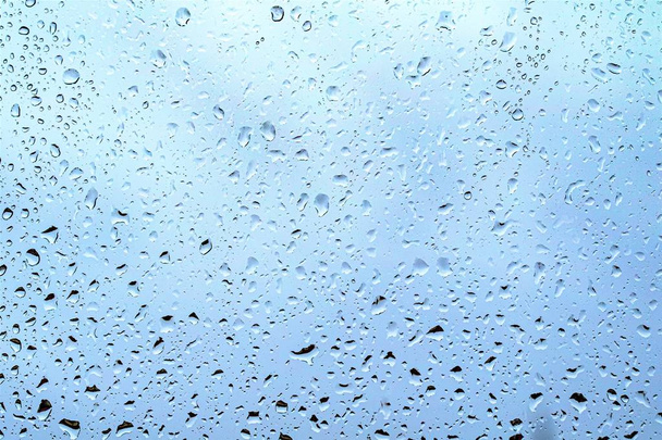 Gotas de lluvia en el vidrio, fondo azul oscuro del cielo fuera de la ventana
. - Foto, Imagen