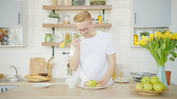 Beautiful blonde man is making breakfast for his girlfriend in the morning - Photo, image