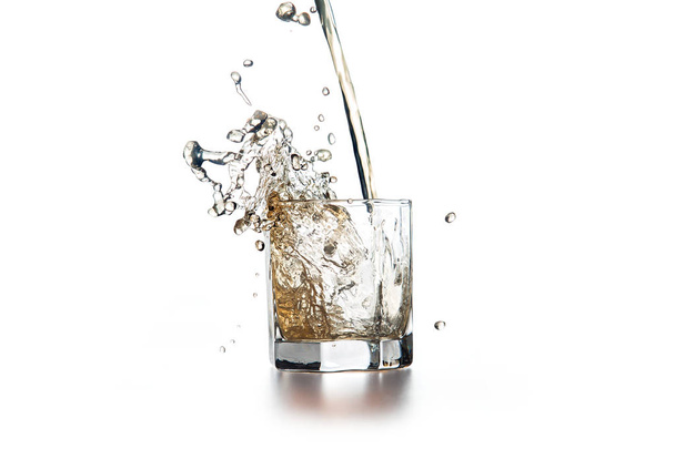 Whisky glas met ijs binnenstromen op lichte achtergrond - Foto, afbeelding