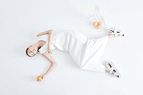 Young stylish woman with oranges lying on floor - Fotoğraf, Görsel
