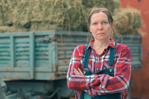 Женщина-фермер позирует перед телегой с сеном
 - Фото, изображение