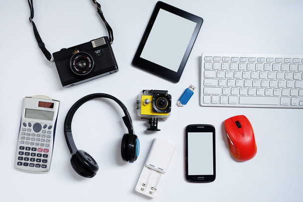 E-kirja lukija matkapuhelimet, kamera, näppäimistö, hiiri ja muistitikut USB. valkoisella taustalla, Käytetyt modernit vempaimet tai elektroniset laitteet päivittäiseen käyttöön konsepti, Top view
 - Valokuva, kuva