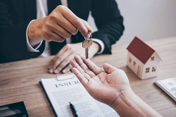 Agent nieruchomości, dając dom klucze do klienta po podpisaniu umowy - Zdjęcie, obraz