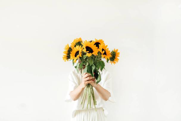Giovane ragazza con mazzo di girasoli in mano su sfondo bianco. Composizione floreale estiva
. - Foto, immagini