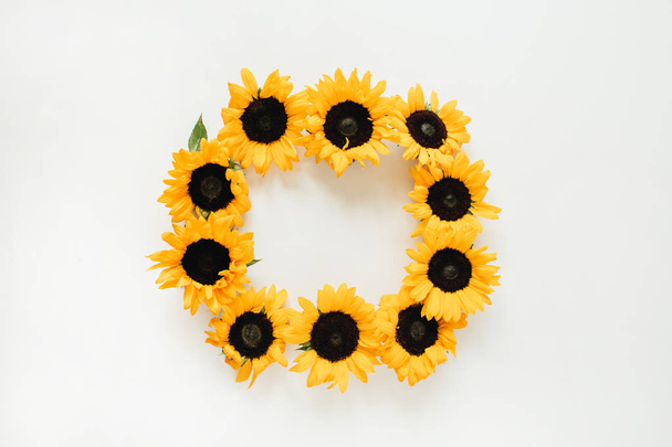Krans frame gemaakt van zonnebloemen met kopieerruimte op witte achtergrond. Platte lay, bovenaanzicht zomerbloemen mock up template. - Foto, afbeelding