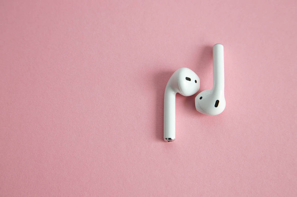 kabellose weiße Kopfhörer ohne Kabel, die nebeneinander auf rosa Hintergrund liegen. Platz für Text - Foto, Bild