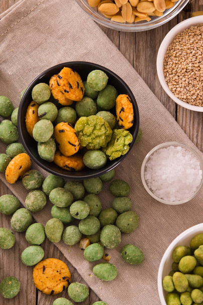 Wasabi coated peanuts on wooden table. - Foto, afbeelding
