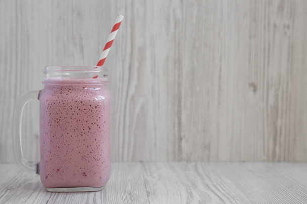 Strawberry banana smoothie in a glass jar over white wooden surf - Foto, immagini
