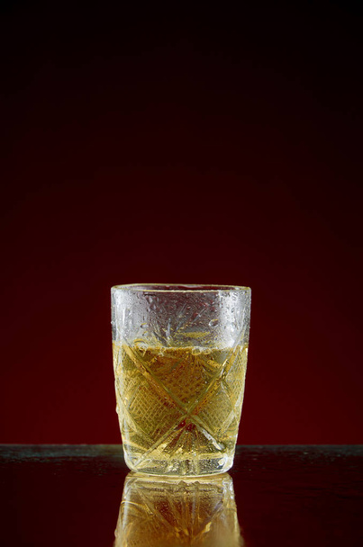 Glass with original alcoholic drink with mint and ice on red background - Fotoğraf, Görsel