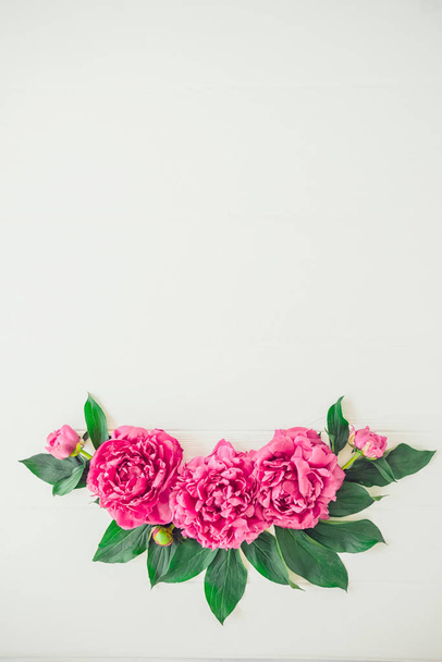 Flower composition made of bright pink buds peony bouquet on a white wooden background. Floral texture mockup. Flat lay, top view. Peony texture. Vintage, retro toning image. Vertical. Copy space. - Фото, зображення