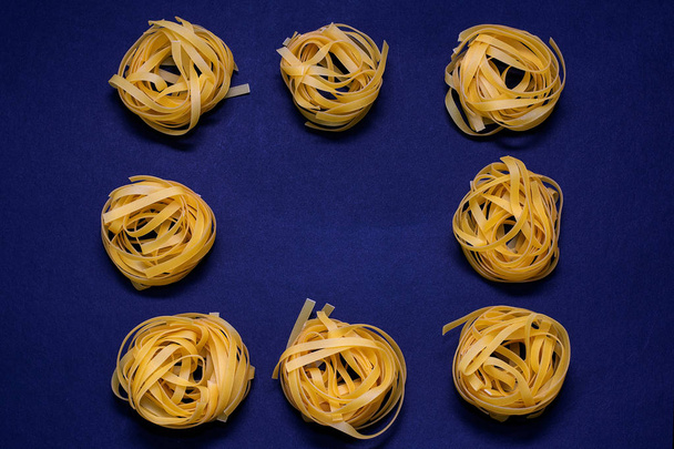 Droge pasta geel op een donkere achtergrond. Italiaans eten - Foto, afbeelding