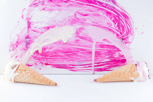 Melted ice cream with chocolate and nuts on a pink background. Two ice cream cones in pop art style. Summer milk dessert in a waffle cone. Summer concept - Foto, Imagen