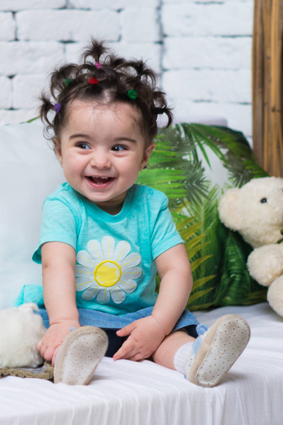 Feliz sorrindo doce bebê menina sentada no sofá com urso brinquedo
 - Foto, Imagem
