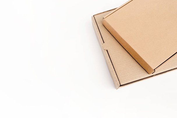 Two flat cardboard packages for goods lie on each other, isolated on a white background. Recyclable eco-friendly material. - Фото, изображение