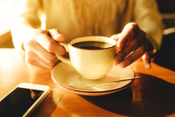 Woman holding in hands cup of coffee on wooden background - Foto, immagini