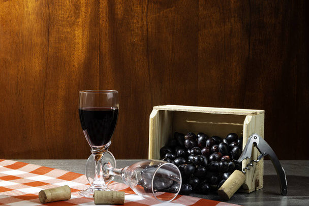 Bottle of red wine in wine cellar for tasting. Red wooden background with wooden box with grapes. Wine tradition and culture concept. - Foto, imagen